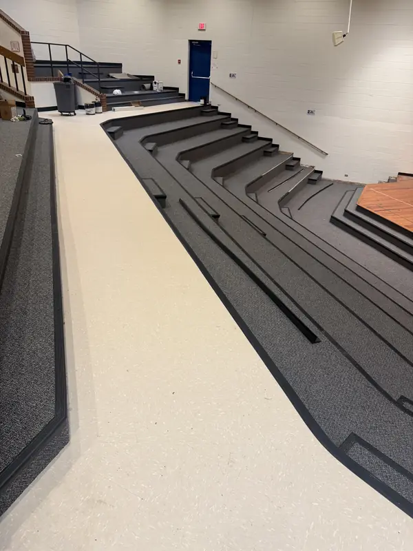 Auditorium flooring with carpeted tiered steps and a resilient vinyl aisle